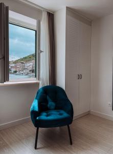 Adriana Zaton في Zaton: كرسي أزرق في غرفة مع نافذة