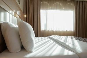 a bedroom with a bed with pillows and a window at Toledo Amman Hotel in Amman