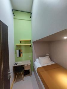 a small bedroom with a bed and a desk at Autumn Living Hotel in Surabaya