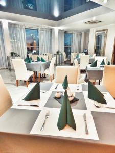 uma sala de jantar com mesas e cadeiras com guardanapos verdes em Hotel Max em Luboń