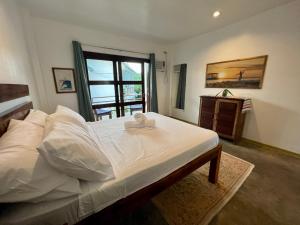a bedroom with a bed with white sheets and a window at Fat Lips Surf Lodge in General Luna