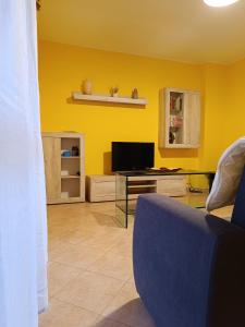 a living room with yellow walls and a tv at Cà Savoia in Bologna