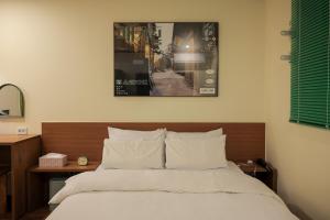 a bed with white sheets and a wooden head board at Jeonju AANK Hotel in Jeonju