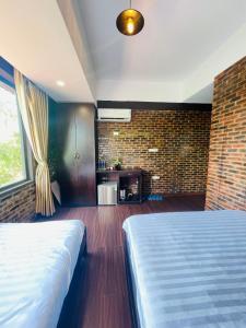 um quarto com uma cama e uma parede de tijolos em Mandarin Homestay Hue em Hue