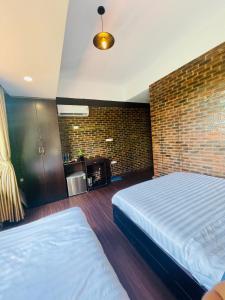 1 dormitorio con 2 camas y pared de ladrillo en Mandarin Homestay Hue en Hue