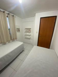 - une chambre avec 2 lits et une porte en bois dans l'établissement Temporada CG - Apartamento no Alto Branco, à Campina Grande