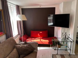 a living room with a red couch and a tv at 100 kvadratmeter. Yderst attraktivt beliggenhed in Copenhagen