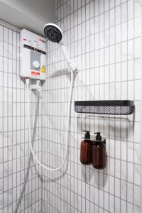 a white tiled wall with a shower head on a wall at A1 Duplex large room wt kitchen in Bangkok