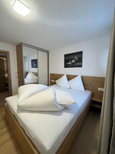 1 dormitorio con 1 cama grande con sábanas y almohadas blancas en Villa Oberbichl en Piesendorf