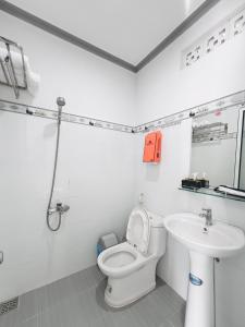a white bathroom with a toilet and a sink at Lavender Muine Hotel in Mui Ne