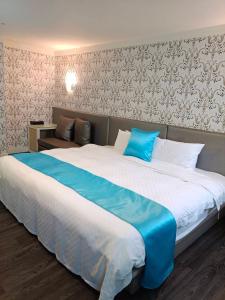 een slaapkamer met een groot bed en een blauwe deken bij HengChang Business Hotel in Keelung