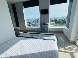 a bed in a room with two large windows at Lavender Muine Hotel in Mui Ne