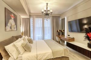 a bedroom with a bed and a desk and a television at Herastrau Luxury Studios in Bucharest
