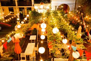 un giardino con luci, sedie, tavoli e panche di Frangipani motel a Galle