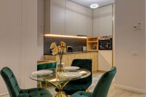 a dining room with a glass table and green chairs at Herastrau Luxury Studios in Bucharest