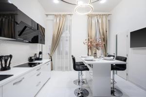 a white kitchen with a table and two chairs at Opera Balkony Luxury Apartment in Budapest