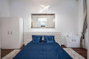 Opera Balkony Luxury Apartment في بودابست: غرفة نوم بسرير ازرق مع مخدات زرقاء