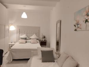 a white bedroom with a bed and a couch at La casa de loto in Alcalá de los Gazules