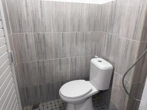 a bathroom with a white toilet in a tiled wall at RedDoorz near Stasiun Pematangsiantar in Pematangsiantar