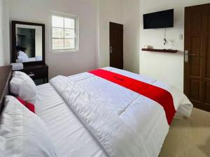 ein Schlafzimmer mit einem großen Bett mit einer roten und weißen Decke in der Unterkunft RedDoorz near Stasiun Pematangsiantar in Pematangsiantar