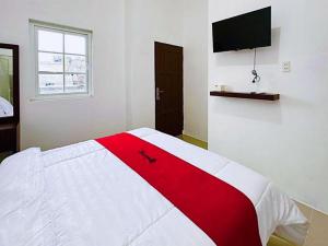 a bedroom with a red and white bed with a tv on the wall at RedDoorz near Stasiun Pematangsiantar in Pematangsiantar