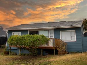 a blue house with a deck and a cloudy sky at 1 Harbour Way in Gansbaai