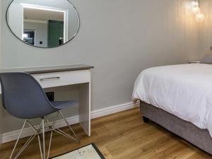 a bedroom with a bed and a desk and a mirror at 1 Harbour Way in Gansbaai