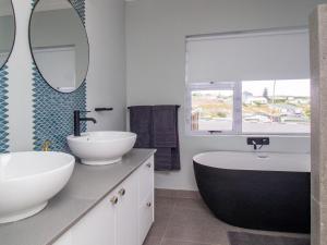 a bathroom with two sinks and a tub and a mirror at 1 Harbour Way in Gansbaai