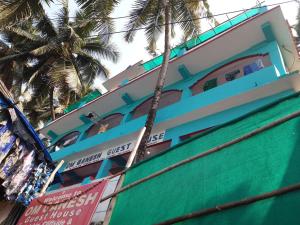 un bâtiment bleu et blanc avec un palmier dans l'établissement Om Ganesh Guest House Cliffside, à Arambol