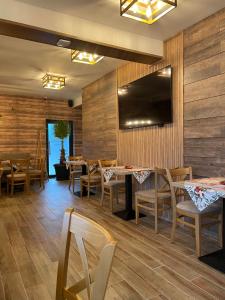 a restaurant with wooden walls and tables and chairs at Zarevata Guest House in Velingrad