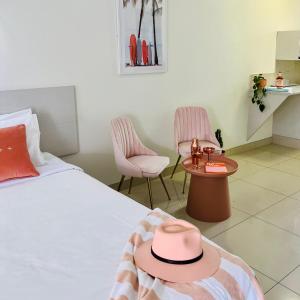 a room with a bed with a hat and two chairs at Bay Motel in Byron Bay