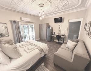 a bedroom with a bed and a couch and a desk at Buffels Place in Pretoria