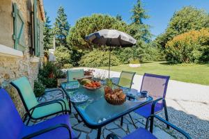 un tavolo con un cesto di frutta e un ombrello di Le Cayroux - Clévacances 3 clés a Blanquefort-sur-Briolance