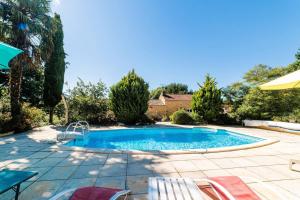 una piscina in un cortile con sedie e ombrellone di Le Cayroux - Clévacances 3 clés a Blanquefort-sur-Briolance