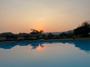 a large swimming pool with a sunset in the background at Nature Trails Durshet, Khopoli in Khopoli