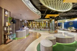 a lobby with tables and chairs in a building at Golden Tulip Springhill Lampung in Bandar Lampung