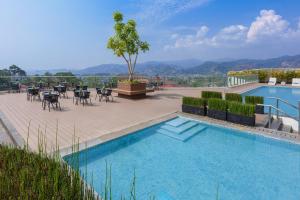a swimming pool with tables and chairs on a patio at Golden Tulip Springhill Lampung in Bandar Lampung