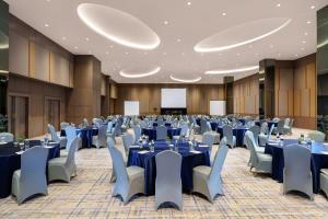 une grande salle de banquet avec des tables et des chaises bleues dans l'établissement Golden Tulip Springhill Lampung, à Bandar Lampung