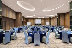 a large banquet hall with blue tables and chairs at Golden Tulip Springhill Lampung in Bandar Lampung +37 photos