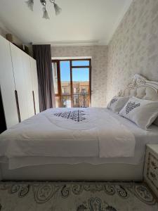 una camera da letto con un grande letto bianco con una finestra di KERUEN SARAY APARTMENTS 6/2 a Türkistan