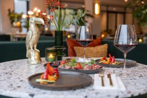 een tafel met twee glazen wijn en eten erop bij Van der Valk hotel Den Haag Wassenaar in Wassenaar