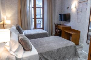 una camera d'albergo con due letti e una televisione di Hotel Granada Centro a Granada