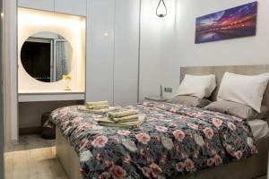 - une chambre avec un lit doté d'une couverture fleurie et d'un miroir dans l'établissement The Golden home 1, au Pirée