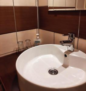 lavabo blanco con grifo en el baño en Tisza Lodge B&B - Panzió en Tiszaderzs