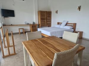 Samalanka Boutique Hotel في Habaraduwa Central: غرفة نوم بسرير وطاولة وكراسي خشبية