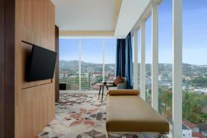 a living room with a television and large windows at Golden Tulip Springhill Lampung in Bandar Lampung