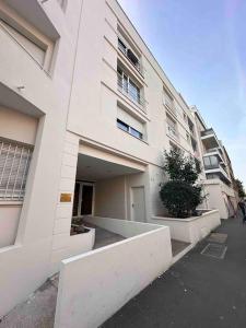 a large white building with a courtyard in front of it at Le Gentil Paris in Gentilly