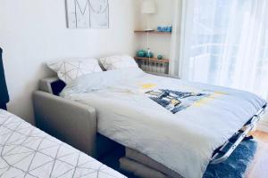 a bed in a bedroom with a white bedspread at Le Gentil Paris in Gentilly