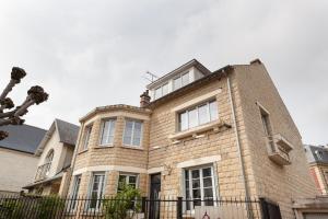 une grande maison en briques avec une clôture devant elle dans l'établissement Les appartements de Chantilly - gare, à Chantilly