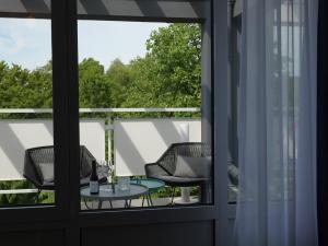 a balcony with chairs and a table and a window at Hotel du Nord Alster - auf der Uhlenhorst - SELF CHECK-IN in Hamburg